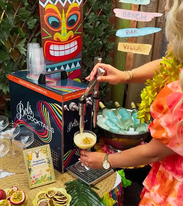 Twee handen die cocktails tappen uit een blauwe cocktailtap van Bols Cocktails. De cocktailtap heeft twee tappen en het logo van Bols Cocktails. Op de achtergrond is een schilderij van een cocktail te zien.